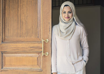 Person smiling while leaning against an open door