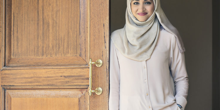 Person smiling while leaning against an open door